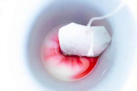 A tea bag creating colorful patterns in a mug Stock Photos