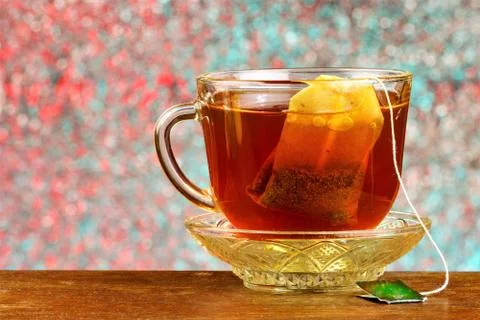 Tea in a bag in a Cup on a saucer, background rainbow lights bokeh. Stock Photos
