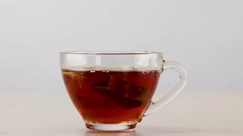 Tea Bag Dropping into Glass Cup of Hot Black Tea Stock Footage 341455023