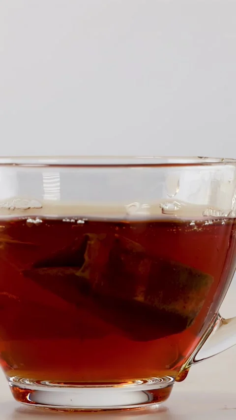Tea Bag Dropping into Glass Cup of Hot Black Tea Stock Footage 342236310