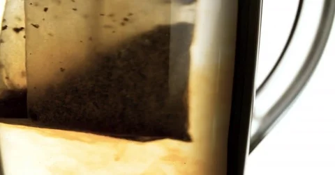 Tea Bag put into hot water brew in glass cup slow motion 4k video macro close up Stock Footage 83466750