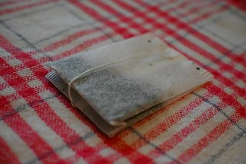 Tea Bag on Red Checkered Tablecloth Close-Up, Home Tea Time Concept 写真素材