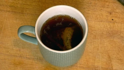 A tea bag is removed from a cup of tea with a spoon Stock Footage 98980210