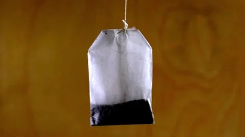 A tea bag on a rope hangs and sways in the wind against a dark wood texture Stock Footage 331832105