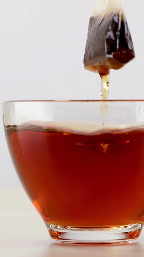 Tea Bag Steeping and Dipping in Glass Cup of Hot Water Stock Footage 342088881