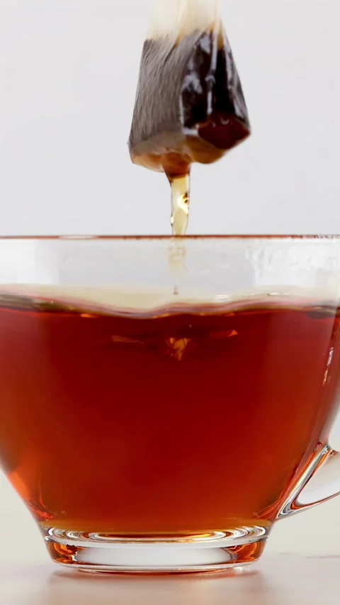 Tea Bag Steeping and Dipping in Glass Cup of Hot Water Stock Footage 342494505