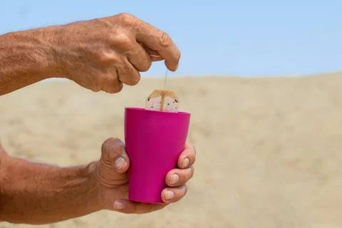 Tea bags in a plastic cup.A man on the beach drinks hot tea. Drinks to quench Stock Photos