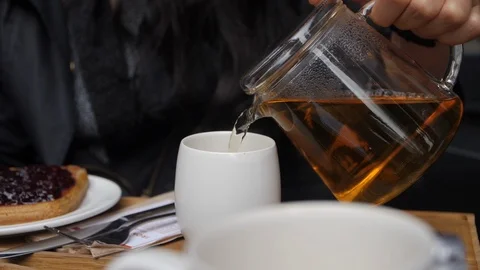Tea Being Poured by Man in Slow Motion from Clear Pot with Black or Red Tea. Stock Footage 89700383