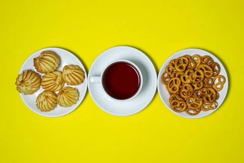 Tea break. A cup of tea with sweets on a yellow background. Stock Photos