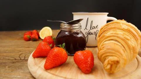 Tea break snacks. Lemon tea, croissant, jar of jam and fresh strawberries. Foto stock