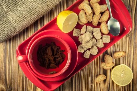 Tea break. Tea in a red ceramic cup on a tray with lump reed sugar, crackers Stock Photos
