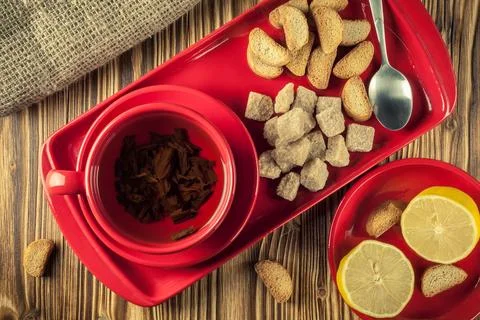 Tea break. Tea in a red ceramic cup on a tray with lump reed sugar, crackers Stock Photos
