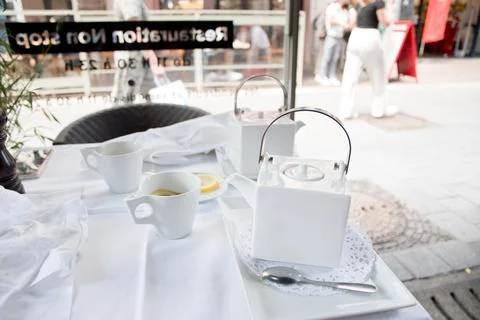 Tea break with a white tea set at a table in a cafe in the city Stock Photos