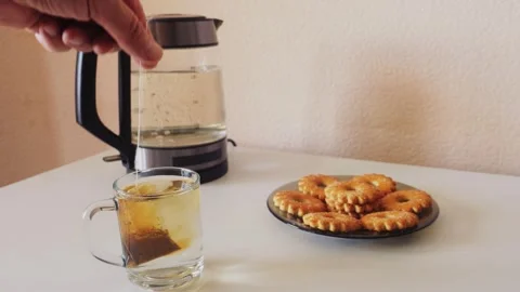 Tea is brewed from a tea bag in a white cup on a table with sweets. Medium .. Stock Footage 321439194