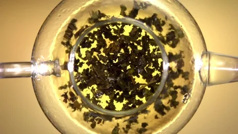 Tea brewing. Green tea leaves swirling in a glass pot. Video stock 71337344