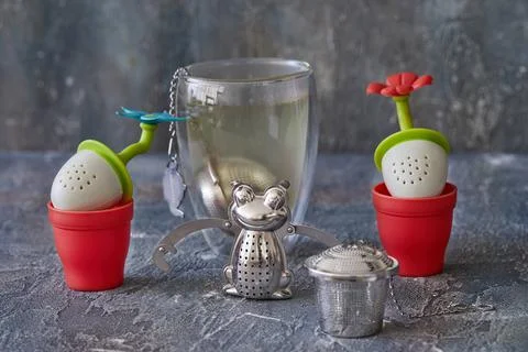 Tea brewing tools in the form of frogs and flowers with glass of tea Stock Photos