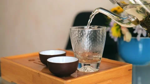 Tea ceremony. Tea is pouring from a teapot into a transparent tea glass Stock Footage 220342073