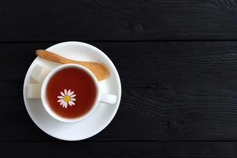 Tea with chamomile in a white cup on a black wooden background Stock Photos