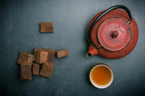 Tea composition with marshmallow, tea cup and iron teapot on dark background. Foto stock
