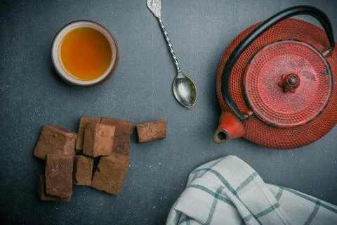 Tea composition with marshmallow, tea cup and traditional teapot on dark back Stock Photos