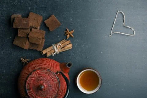 Tea composition with marshmallow, tea cup and traditional teapot on dark back Stock Photos