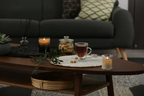 Tea, cookies and decorative elements on wooden table in living room Stock Photos