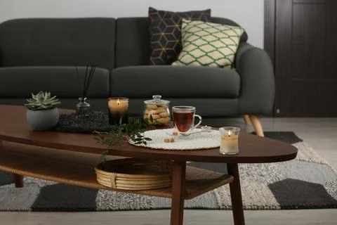 Tea, cookies and decorative elements on wooden table in living room Stock Photos