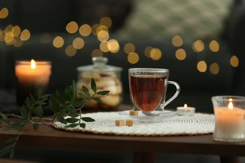Tea, cookies and decorative elements on wooden table against blurred lights i Stock Photos
