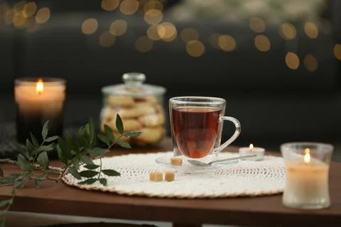 Tea, cookies and decorative elements on wooden table against blurred lights i Stock Photos