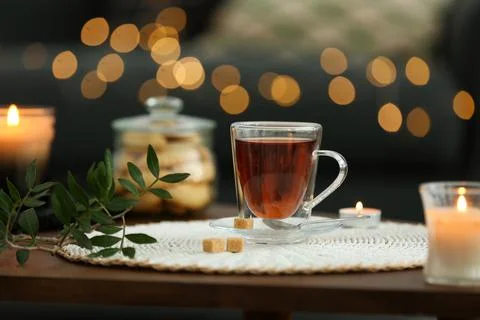 Tea, cookies and decorative elements on wooden table against blurred lights i Stock Photos