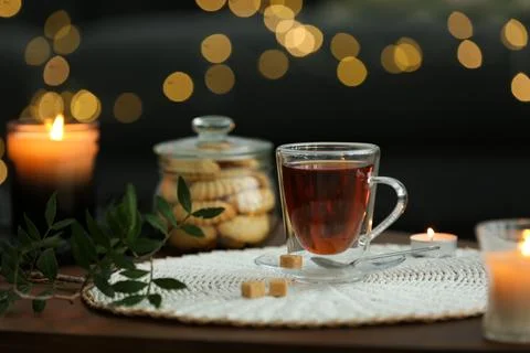 Tea, cookies and decorative elements on wooden table against blurred lights.. Stock Photos
