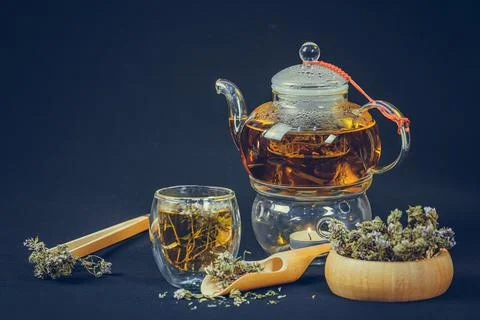 Tea cup and teapot with thyme flower on black background. Stock Photos