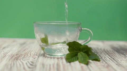 Tea cup with fresh mint leaves on a table on a green background with copy space. Stock Footage 310252519