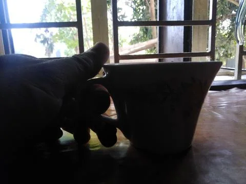 Tea cup on hand in the home window. Фото