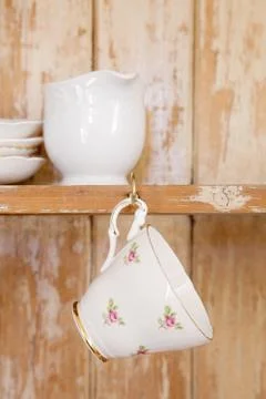 Tea cup hanging on a hook in old wooden cupboard Stock Photos