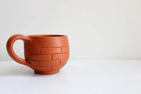 Tea cup made of red soil placed isolated. brick style pattern on the outer side  Stock Photos