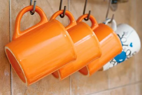 Tea cup orange hang on hooks on the wall Stock Photos