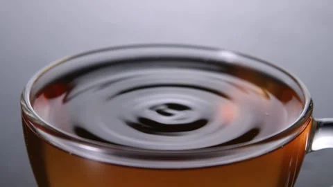 Tea drop falling in full glass cup of tea 動画素材 166403859