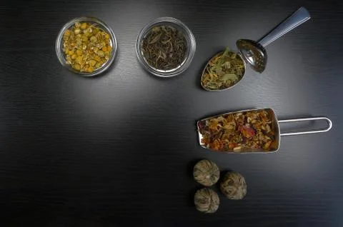 Tea elements with spoon and tea flowers at black wooden background Stock Photos