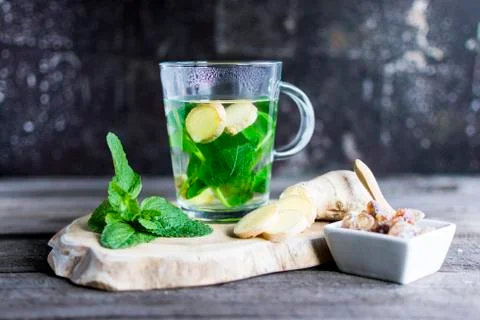 Tea with fresh mint and ginger pieces on a wooden board. Stock Photos