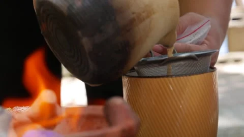 Tea is gently poured through a metal strainer into a mug, highlighting a moment Stock Footage 309933653
