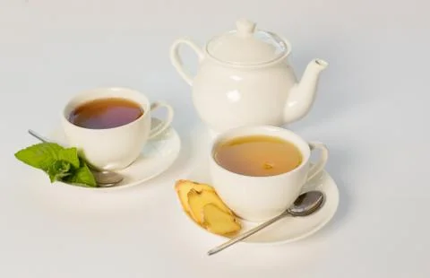 Tea with ginger and mint on white background cups and teapot Stock Photos