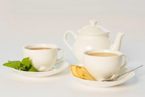 Tea with ginger and mint on white background cups and teapot Stock Photos