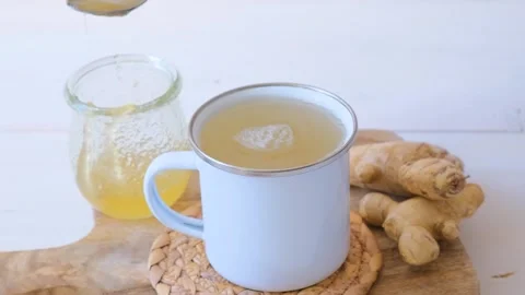 Tea with ginger. A woman's hand adds honey to ginger tea. Stock Footage 287009327