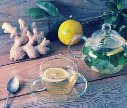 Tea in glass mug with ginger root, lemon and mint - ingredients for healthy t Stock Photos