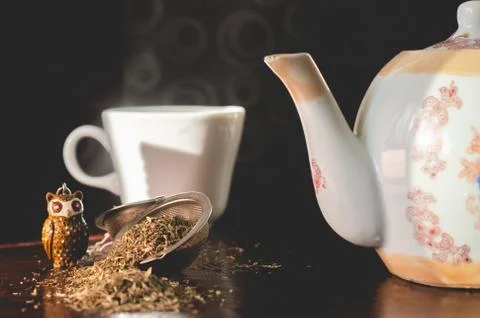 Tea infuser / filter with natural thyme leaves, a white teapot and a white cu Foto stock