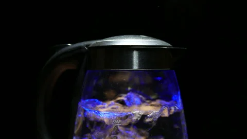 Tea kettle with boiling water on a black background, Stock image