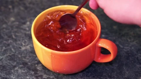 Tea in a large orange cup stir a teaspoon Stock Footage 103123192