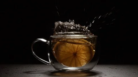 Tea. A lemon falls into a cup of tea. Shot from slow motion. Video stock 128940799