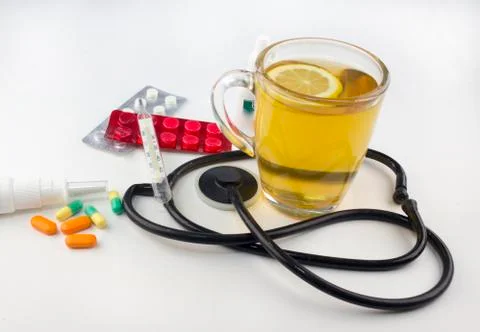 Tea with lemon, thermometer, tablets on white background Stock Photos